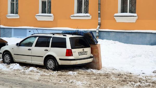Фотофакт: в Архангельске во время очистки крыши машину прикрыли матрасами